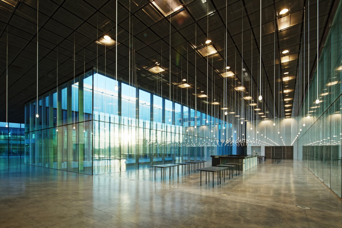Interior of the Estonian National Museum with glass walls, ceiling lights, and minimalist seating.