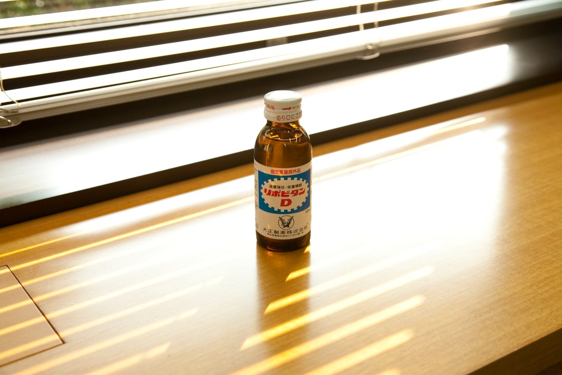 Lipovitan D bottle displayed on a wooden surface under bright fluorescent lighting.