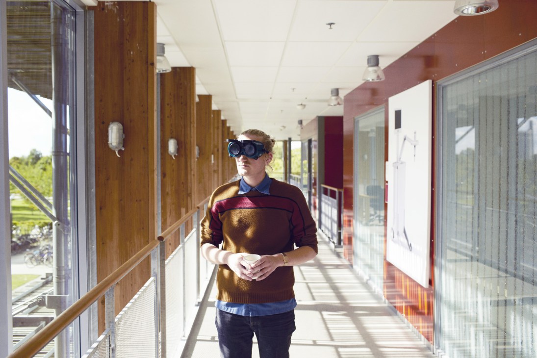 Student wearing goggles simulating vision impairment in a bright corridor at Lund University, Sweden.