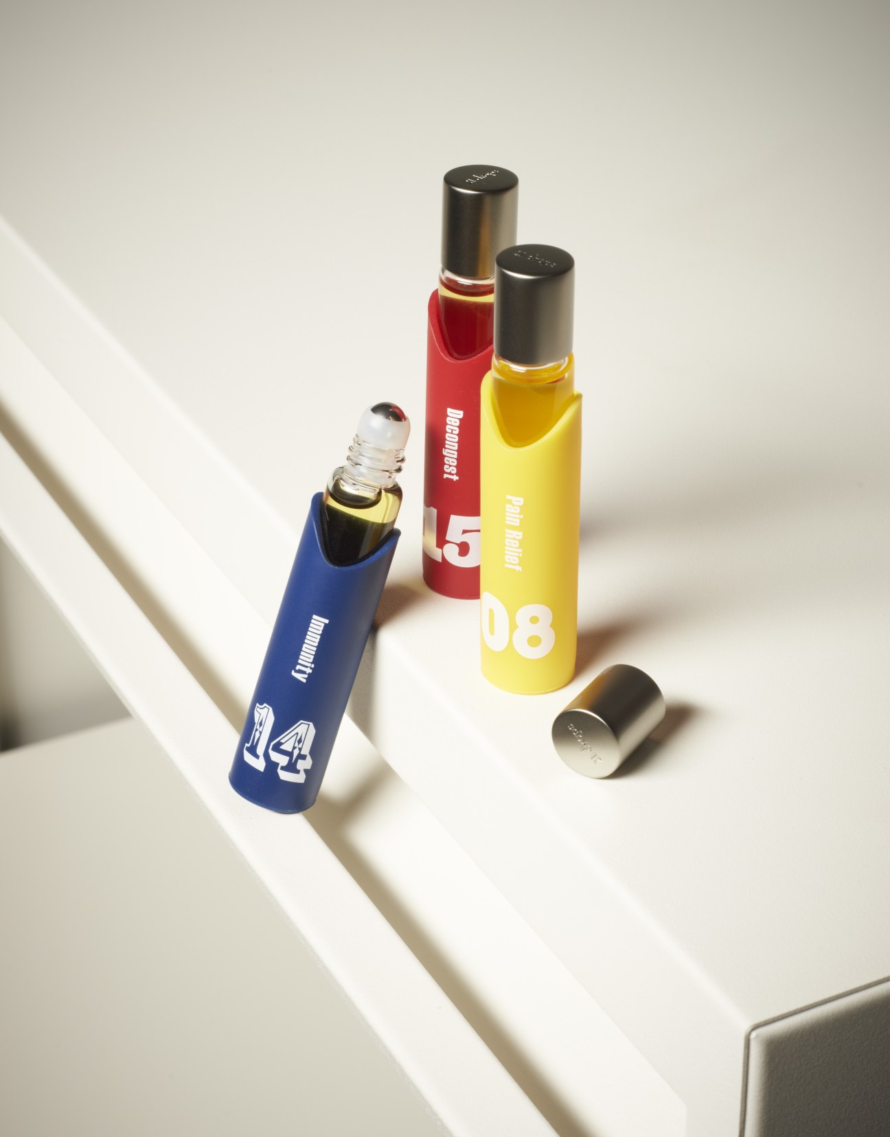 Three colorful rollerball essential oil bottles from 21 Drops aromatherapy in blue, red, and yellow with black caps.