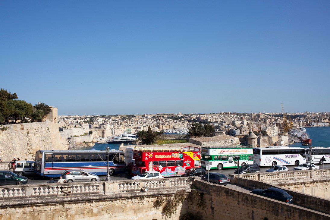 Valletta's Grand Harbour with colorful buses, stone fortifications, and Mediterranean Sea views.