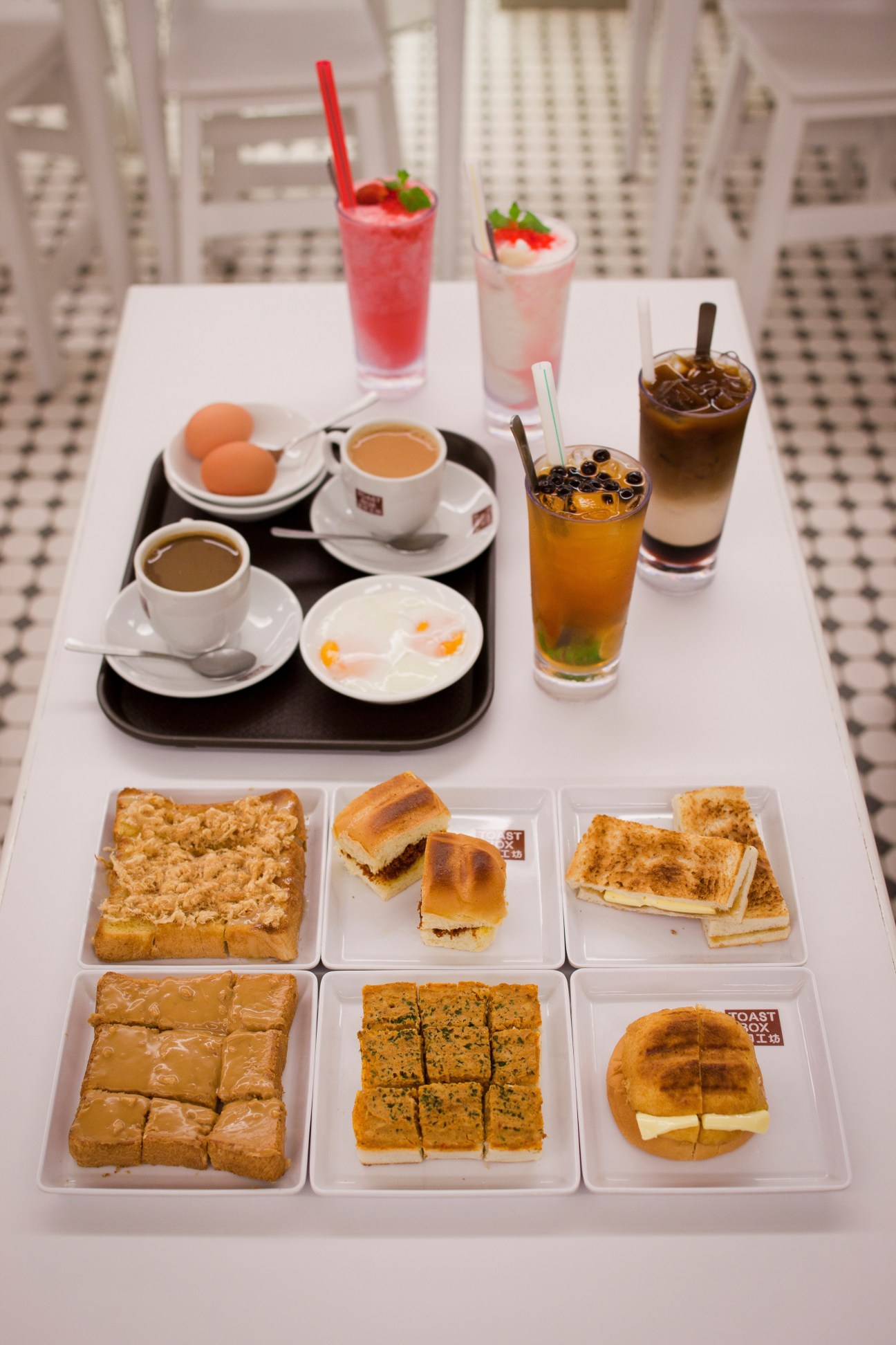 Spread of different toasts from Toast Box with coffee, eggs, and beverages arranged on a white table.