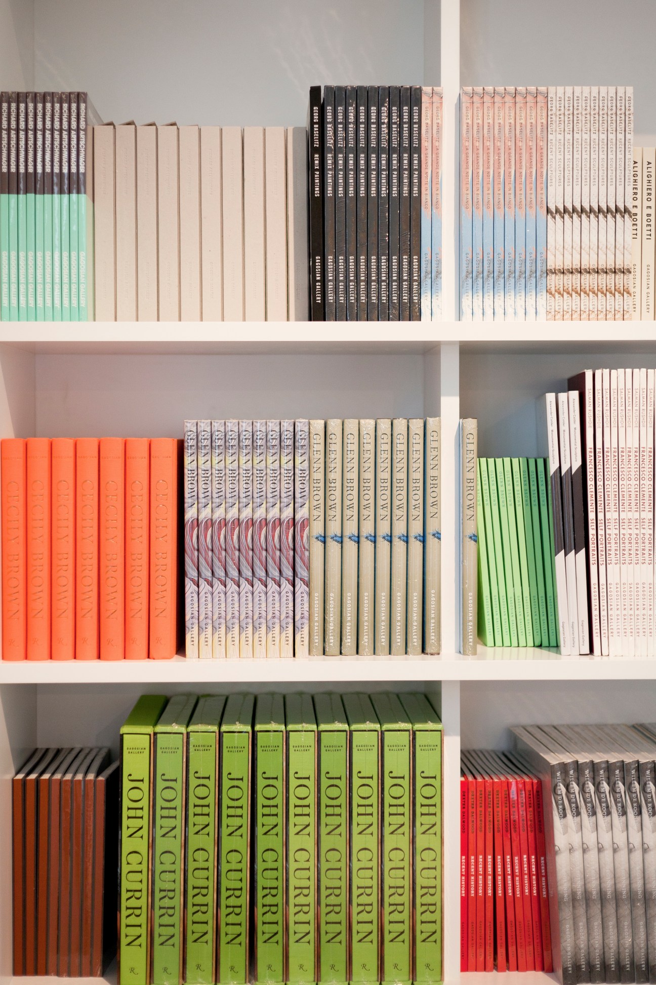 Shelves displaying organized collections of art books and catalogues with colorful spines in various colors including green, orange, red, black and cream.