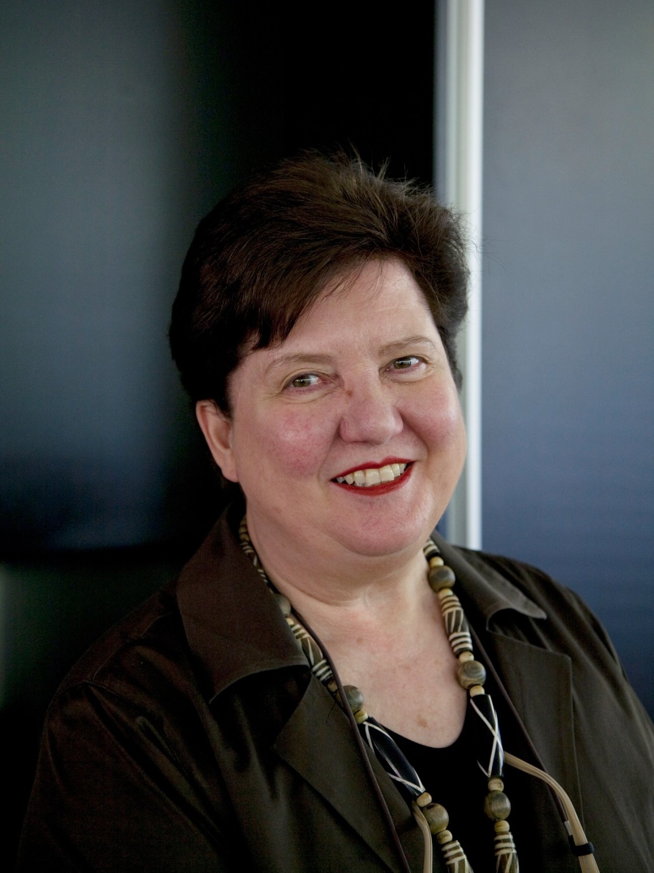 Portrait of Ursula Capaul, co-owner of Alpa cameras, smiling against a white wall.