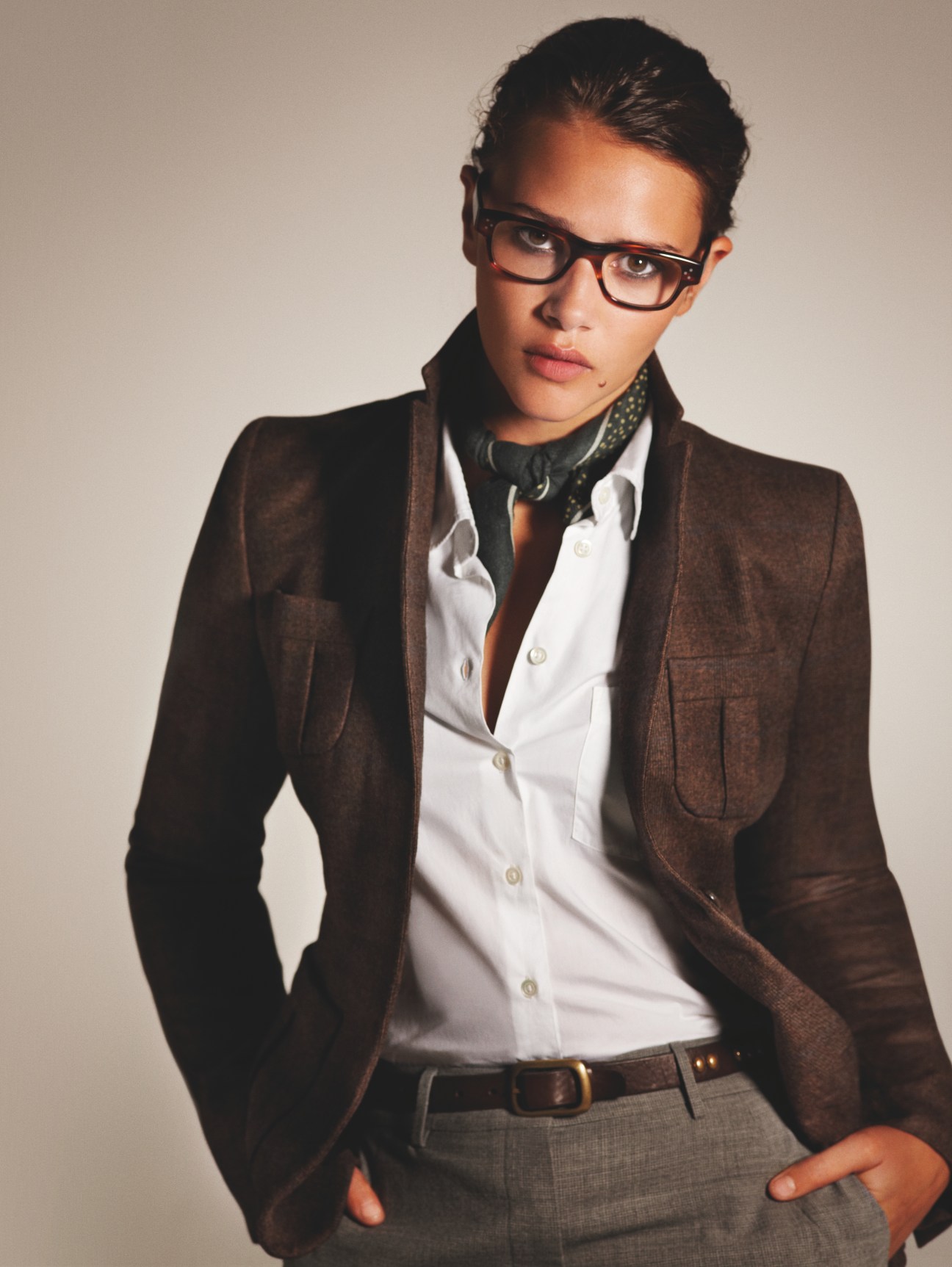 Woman wearing brown Salvatore Ferragamo jacket, white Margaret Howell shirt, and Oliver Peoples glasses with patterned scarf.