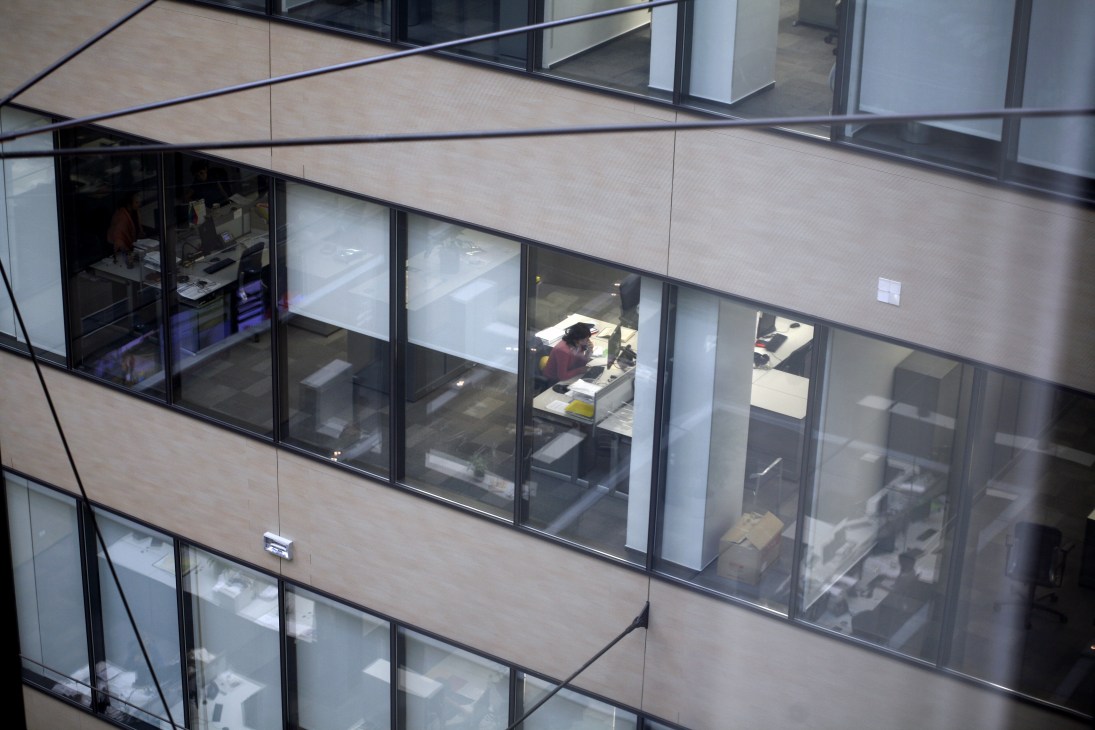 Interior view of RFE/RL's Prague broadcast center showing glass-fronted offices with workers at desks across multiple floors.