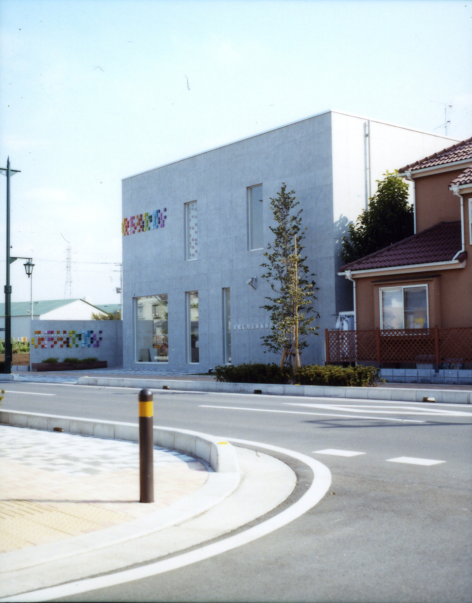 Sugamo Shinkin Bank's Niiza branch exterior with colorful logo squares on grey concrete facade.