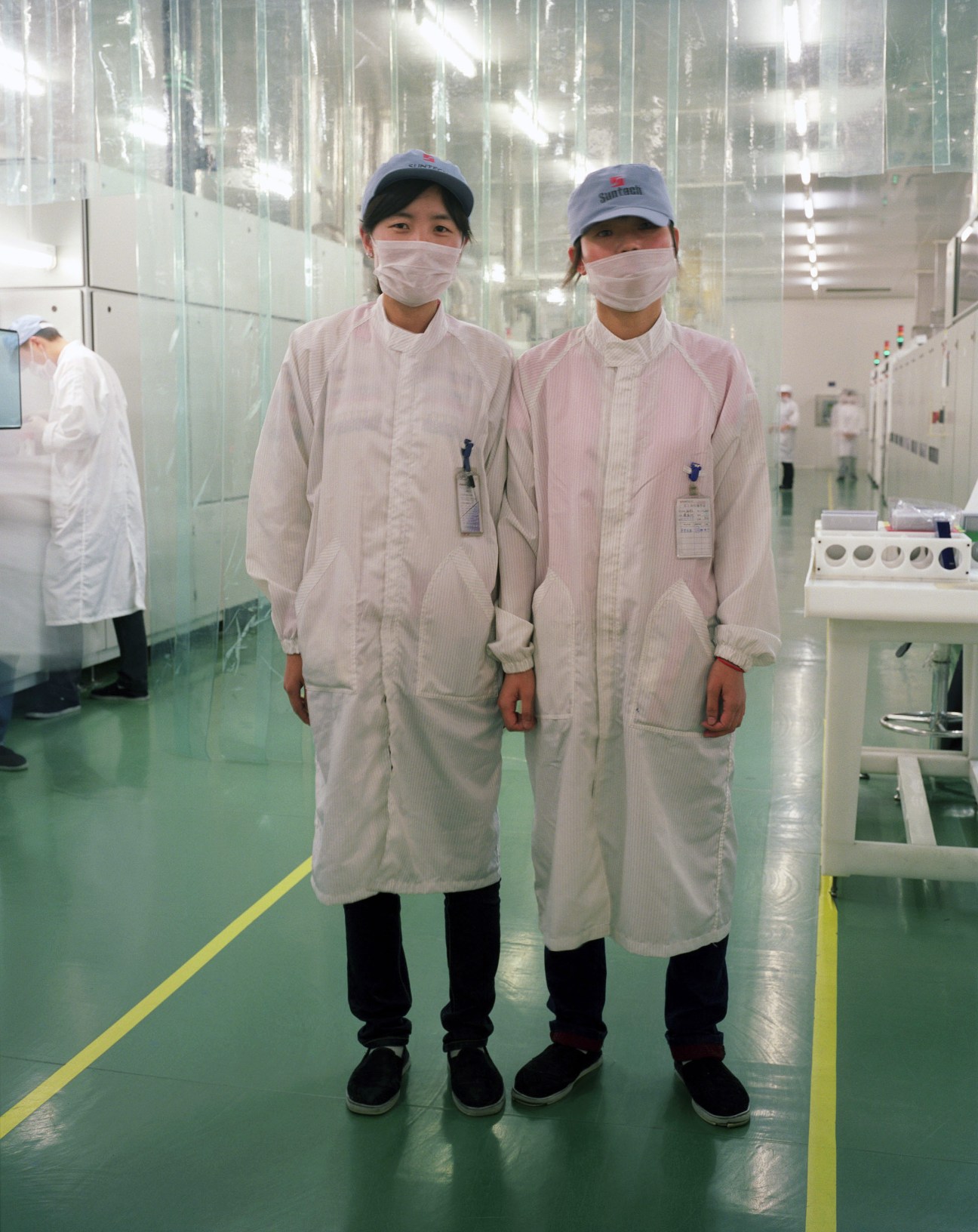 Two workers in white protective suits and masks stand in a clean laboratory at Suntech.