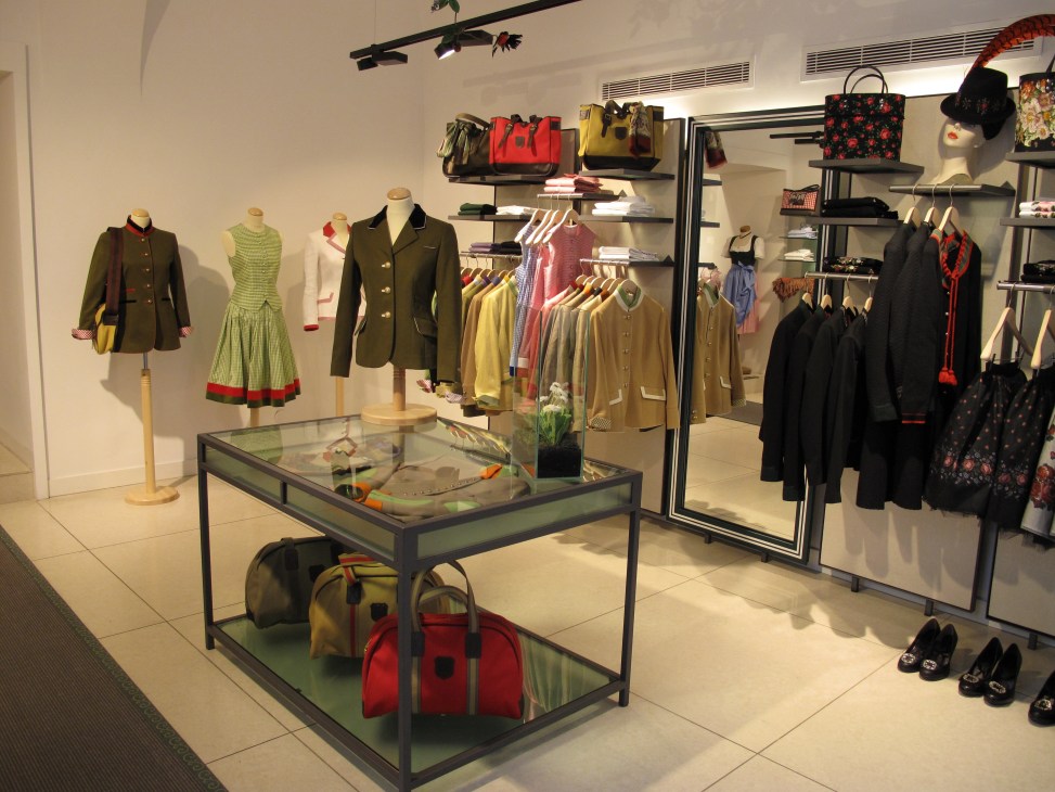 Interior of Rosen & Co clothing boutique in Vienna displaying traditional Austrian tracht jackets on mannequins and hangers with colorful handbags and accessories.