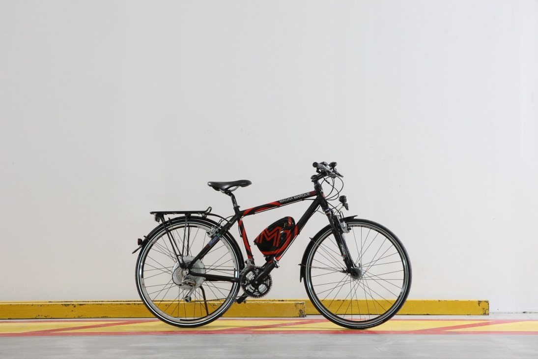BionX electric bike system with red battery pack mounted on frame against yellow and red striped background.