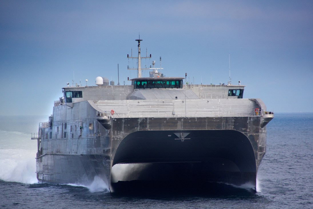 USNS Spearhead catamaran military ship with wide hull moving through ocean water.