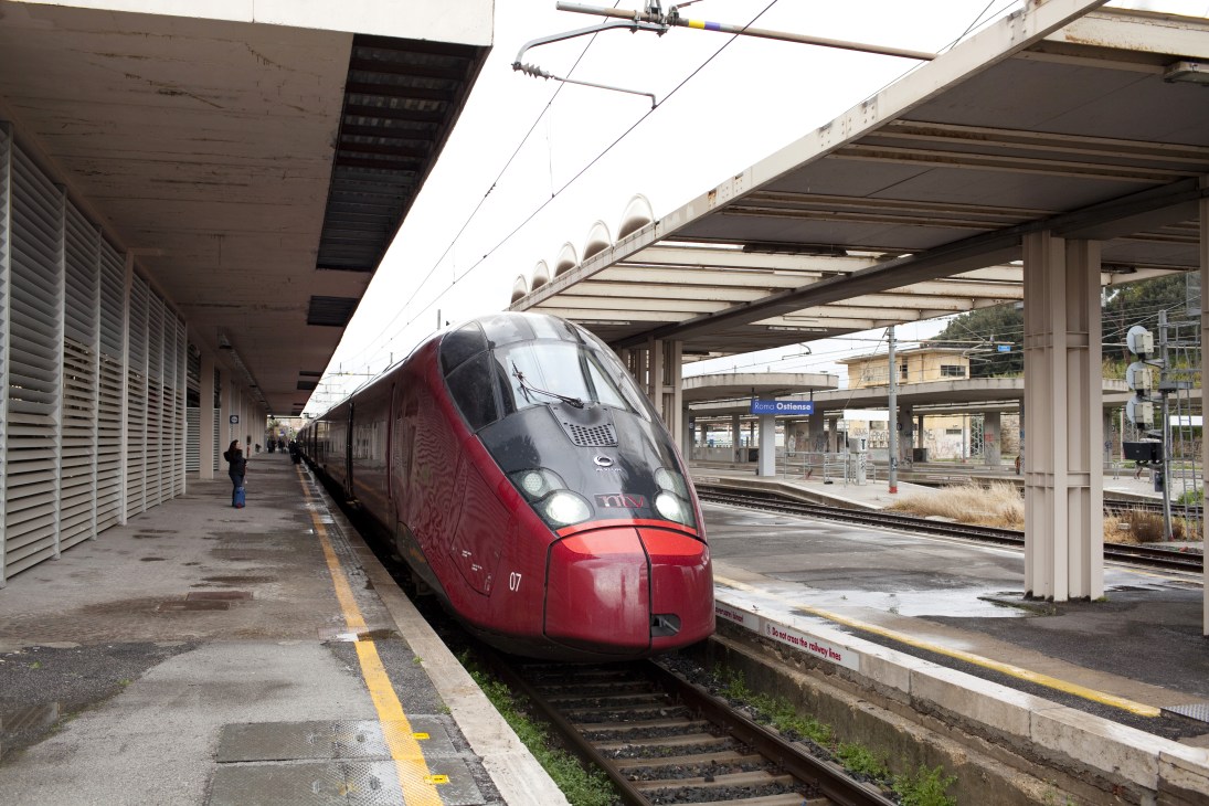 Red and black NTV Italo high-speed train at Rome's Ostiense station platform.