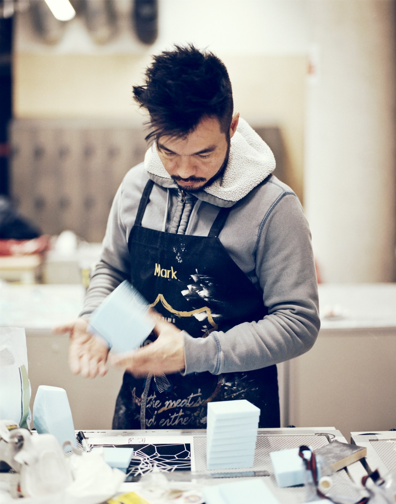 Student wearing apron works at table in 3D Digital Manufacturing workshop.