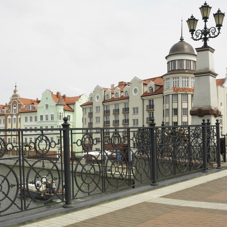 Colorful waterfront buildings with German-style architecture and ornamental ironwork railing in Kaliningrad.