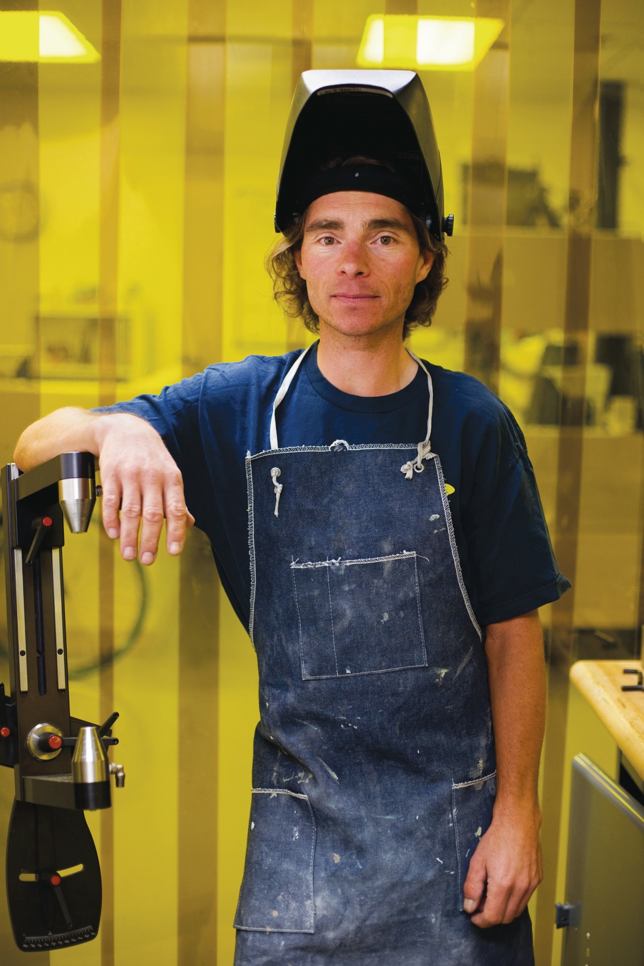 Chris D'Alusio, Globe's director of advanced R&D, in the workshop wearing a welding helmet and denim apron.