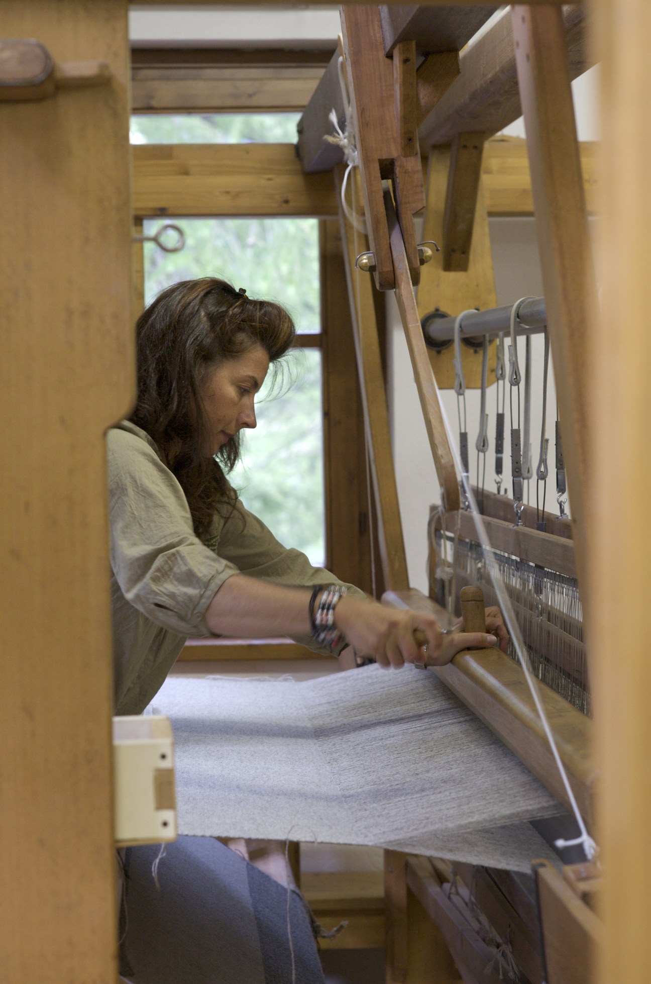 Emy Maguet working at a traditional wooden loom in the Les Tisserands Cooperative.