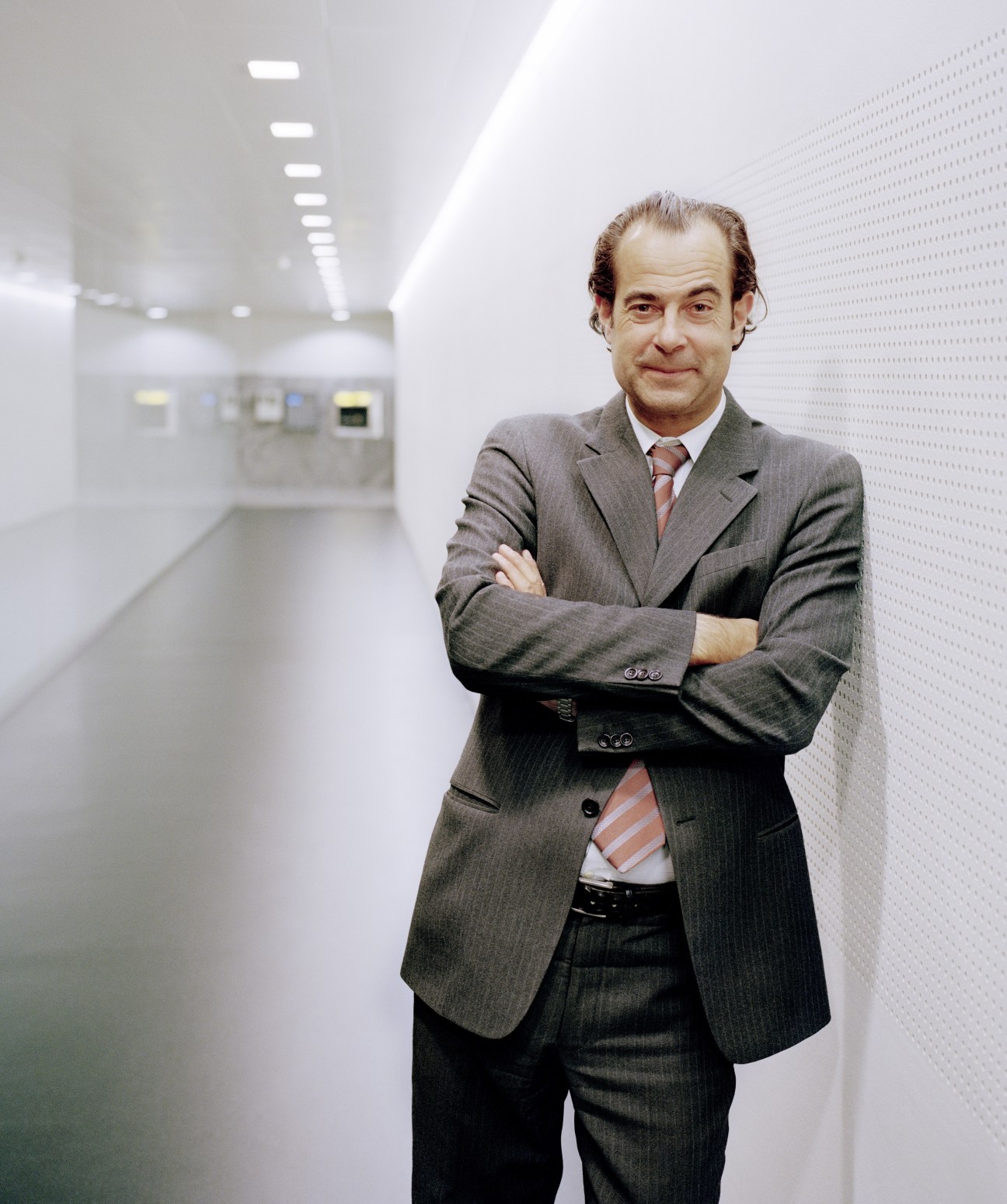 Frank Marthaler, Swiss Post's executive vice president, stands in a modern white corridor with arms crossed.