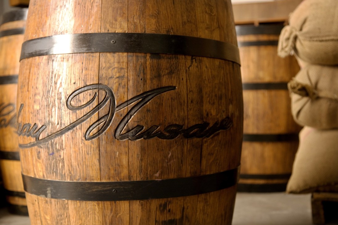 Oak barrel with Château Musar engraved marking and metal bands in winery cellar.