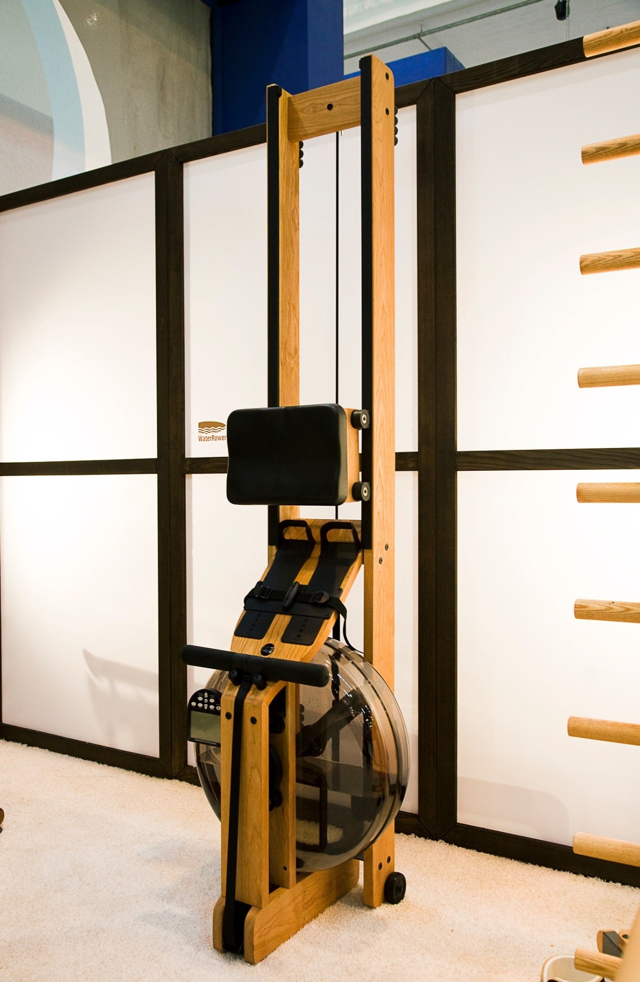 Water Rower's wooden rowing machine with natural wood frame and black seat displayed at a trade show.