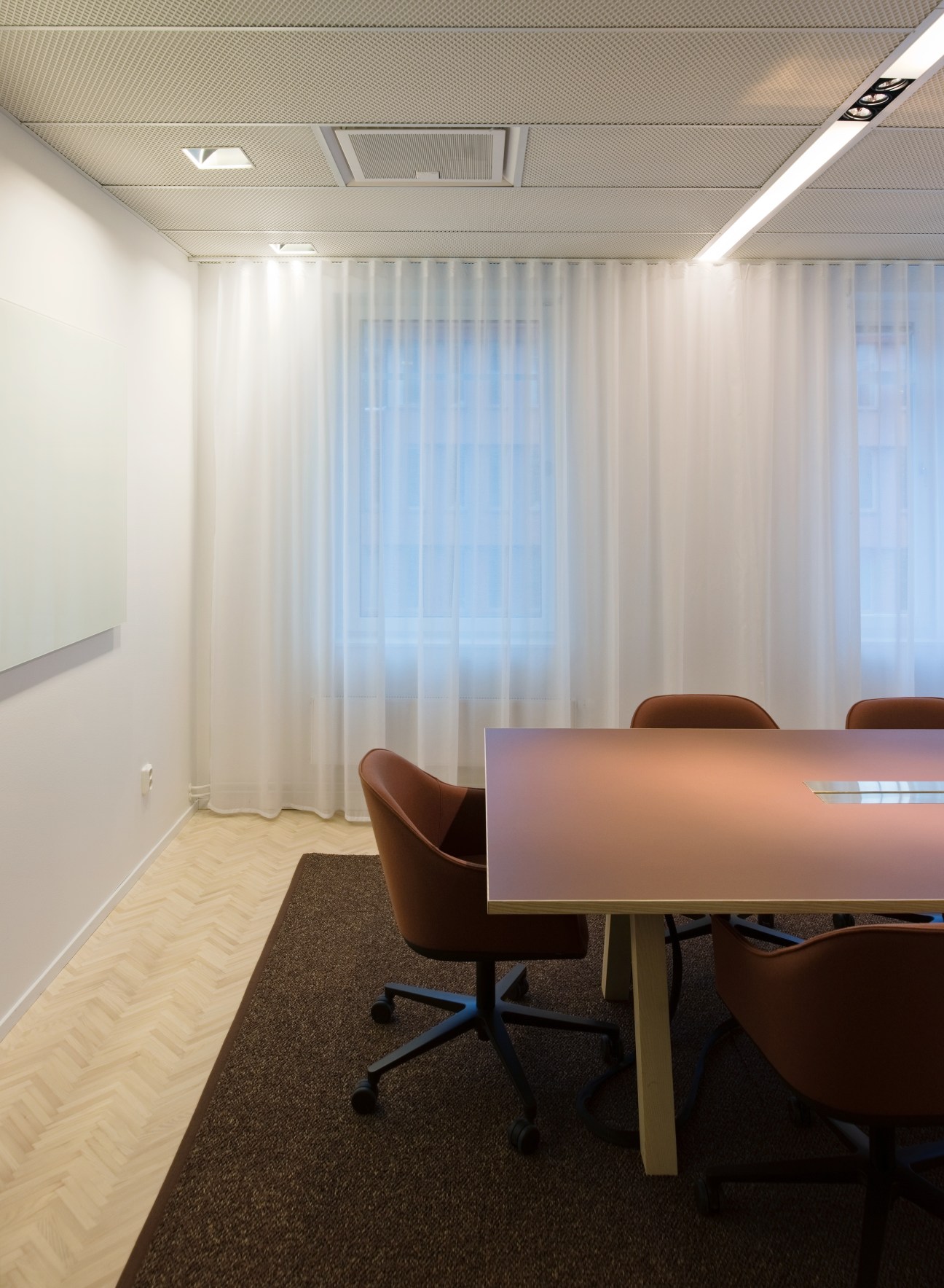 Modern conference room with brown leather chairs, wooden table, white curtains and minimalist ceiling design.