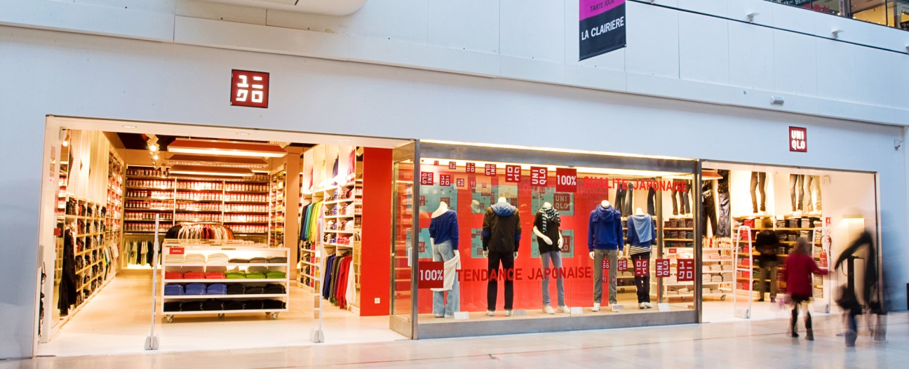 Uniqlo storefront at La Défense shopping center in Paris with red branding and clothing displays.