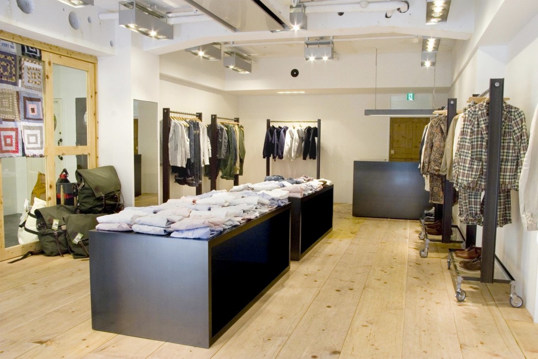 Interior of Engineered Garments flagship store in Tokyo with clothing displays and wooden flooring.