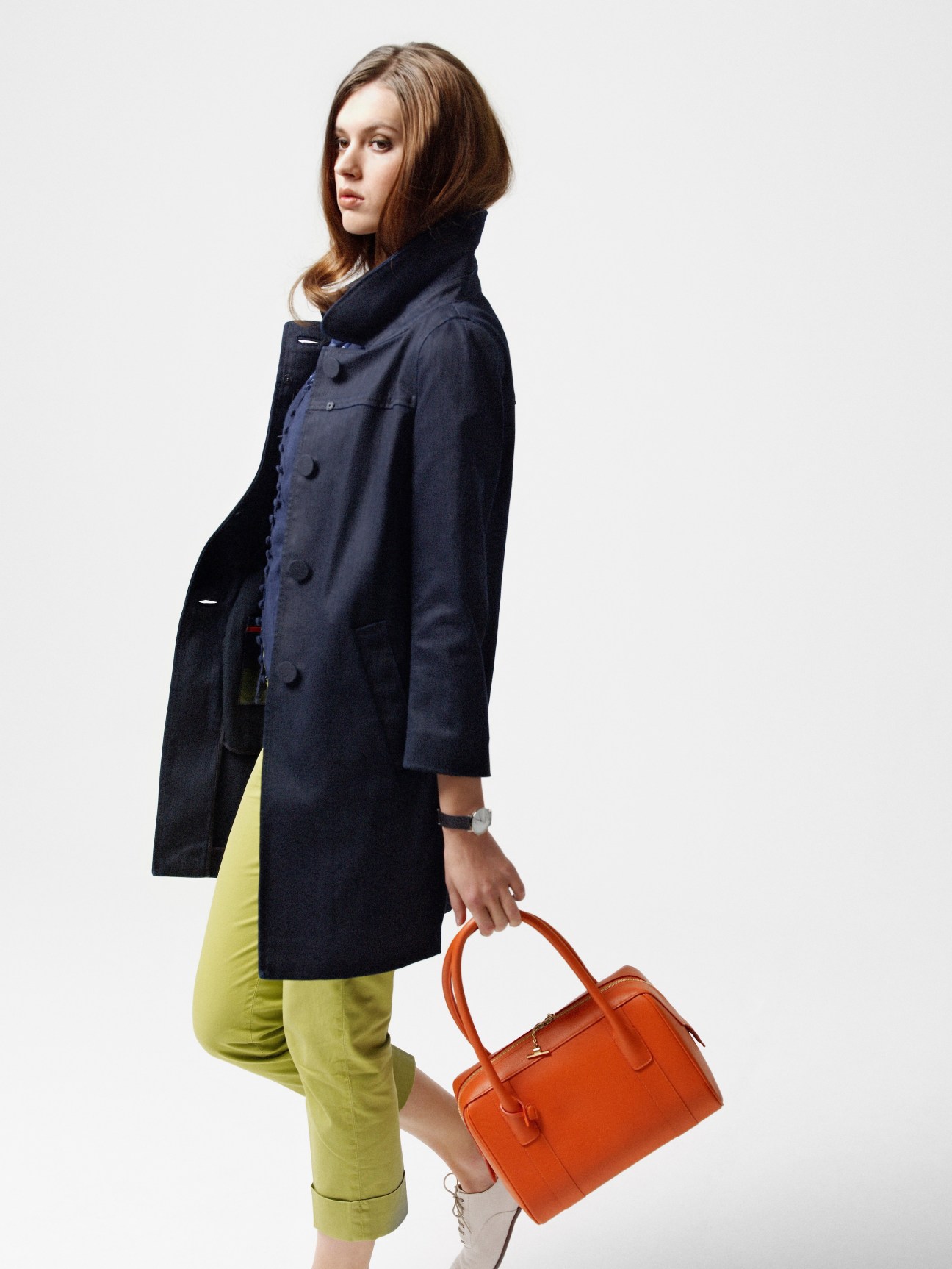 Model Taisia Melnyk wearing a Prada navy coat, Thomas Pink cardigan and blouse, Incotex yellow trousers, Margaret Howell shoes, Georg Jensen watch, and Delvaux orange bag.