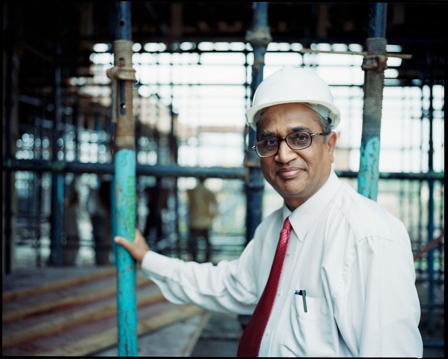 Dr Ashok Kolaskar wearing a hard hat and glasses at an industrial facility.