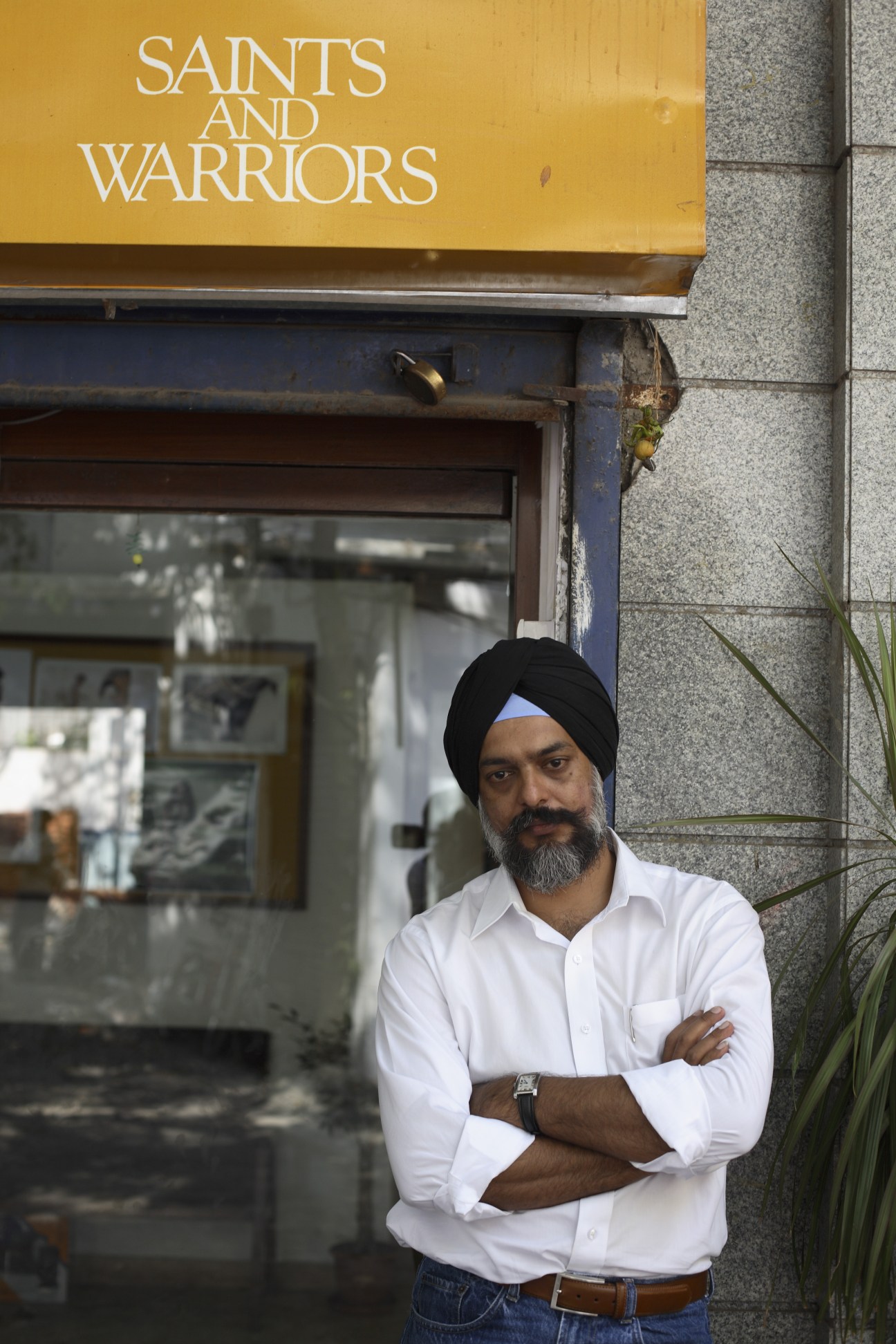 Pushpinder Singh, a Sikh man wearing a black turban and white shirt, stands outside the Saints & Warriors advertising agency in Mumbai.