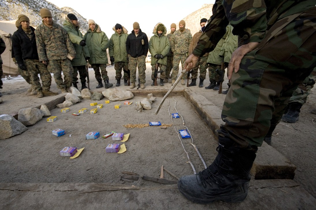Marines and ANA role players stand around a ground display during a training exercise in Nevada mountains.