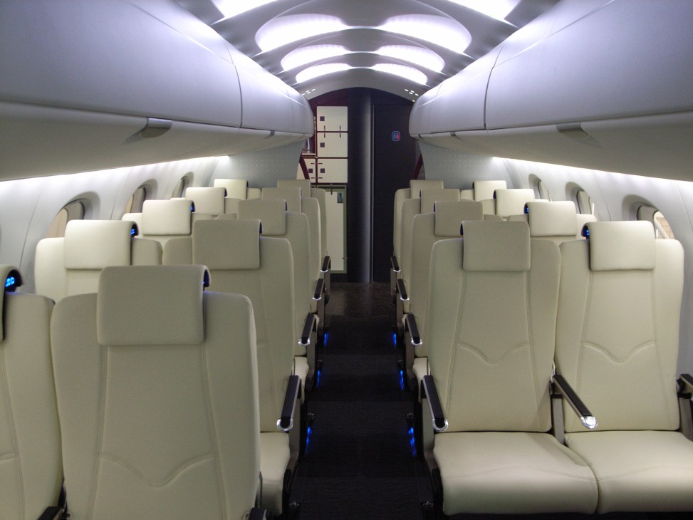 Interior cabin of Mitsubishi Regional Jet with cream-colored seats and modern lighting design.