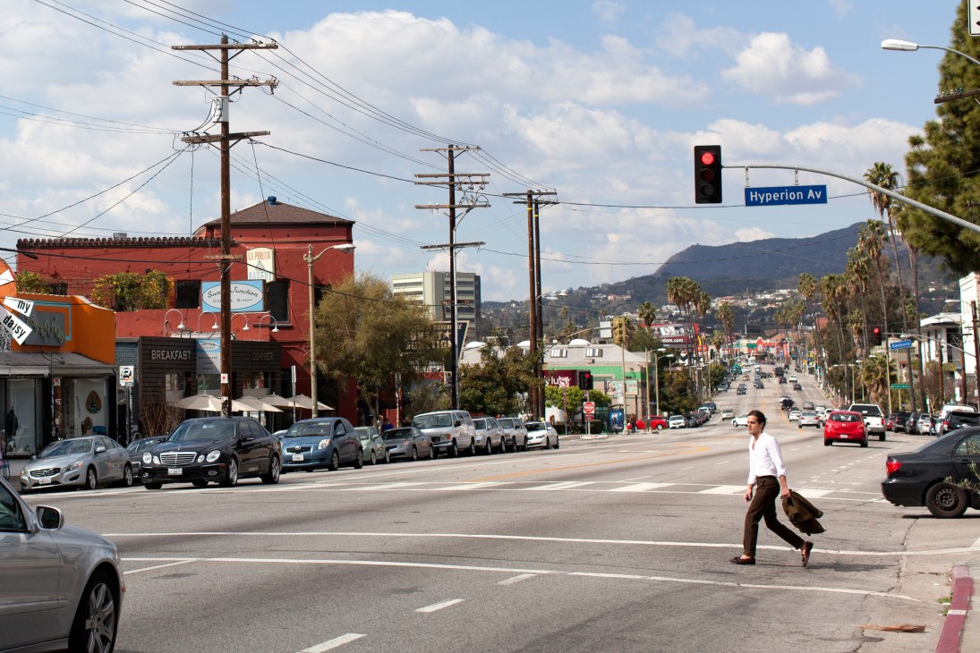 Hyperion Avenue and Sunset Boulevard intersection in Silver Lake with palm trees, mountains, and a red building visible.