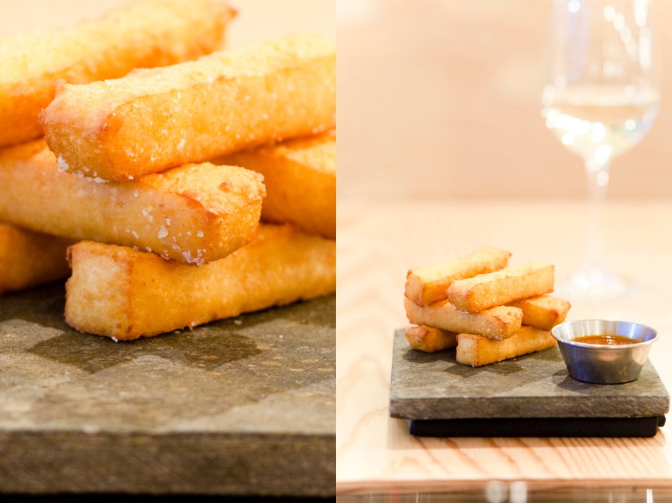 Golden-fried pastries dusted with sugar on slate serving boards with dipping sauce.