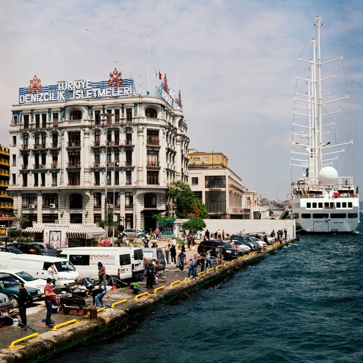 Fishing from the docks in Karakoy with historic Ottoman-era building and cruise ship.