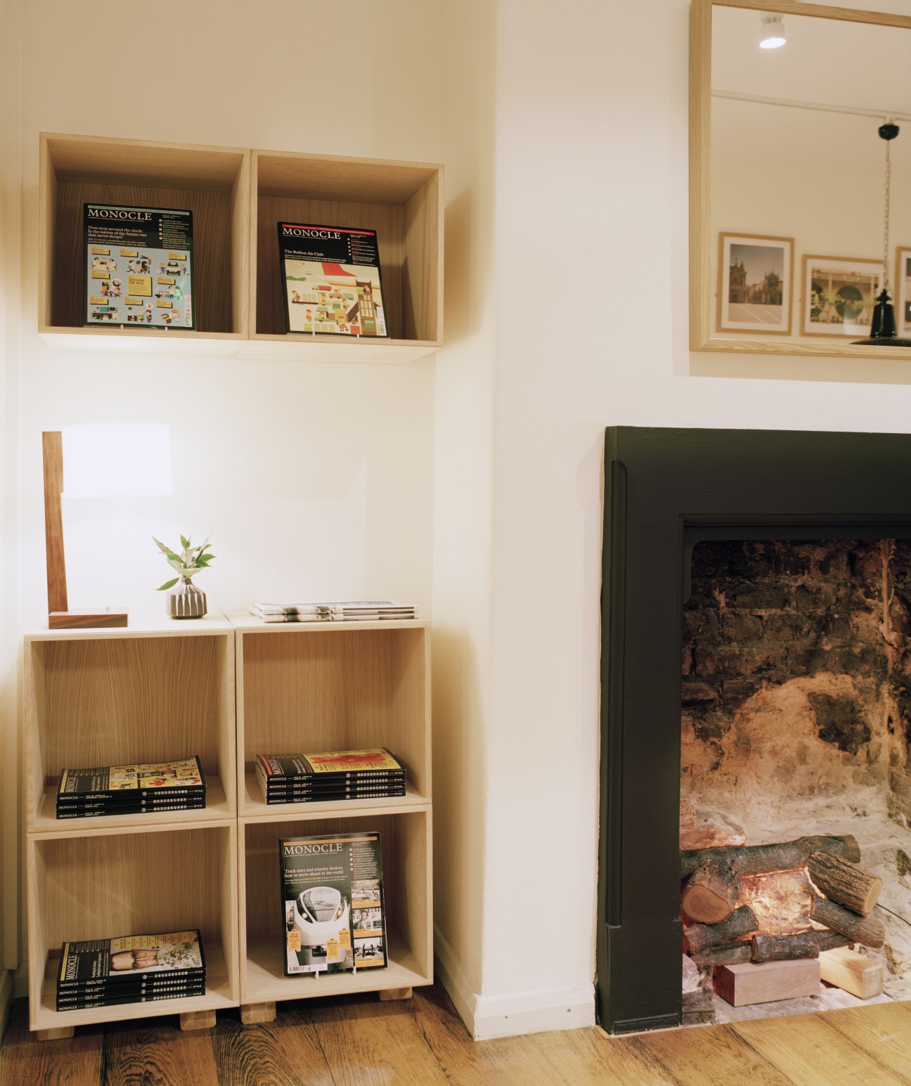 White oak shelving units displaying Monocle magazines and decorative items in a café interior.