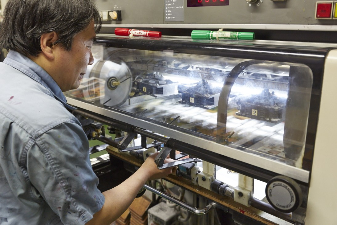 A printer operates a Komori Lithrone printing press at Daito Bijutsu factory in Tokyo.