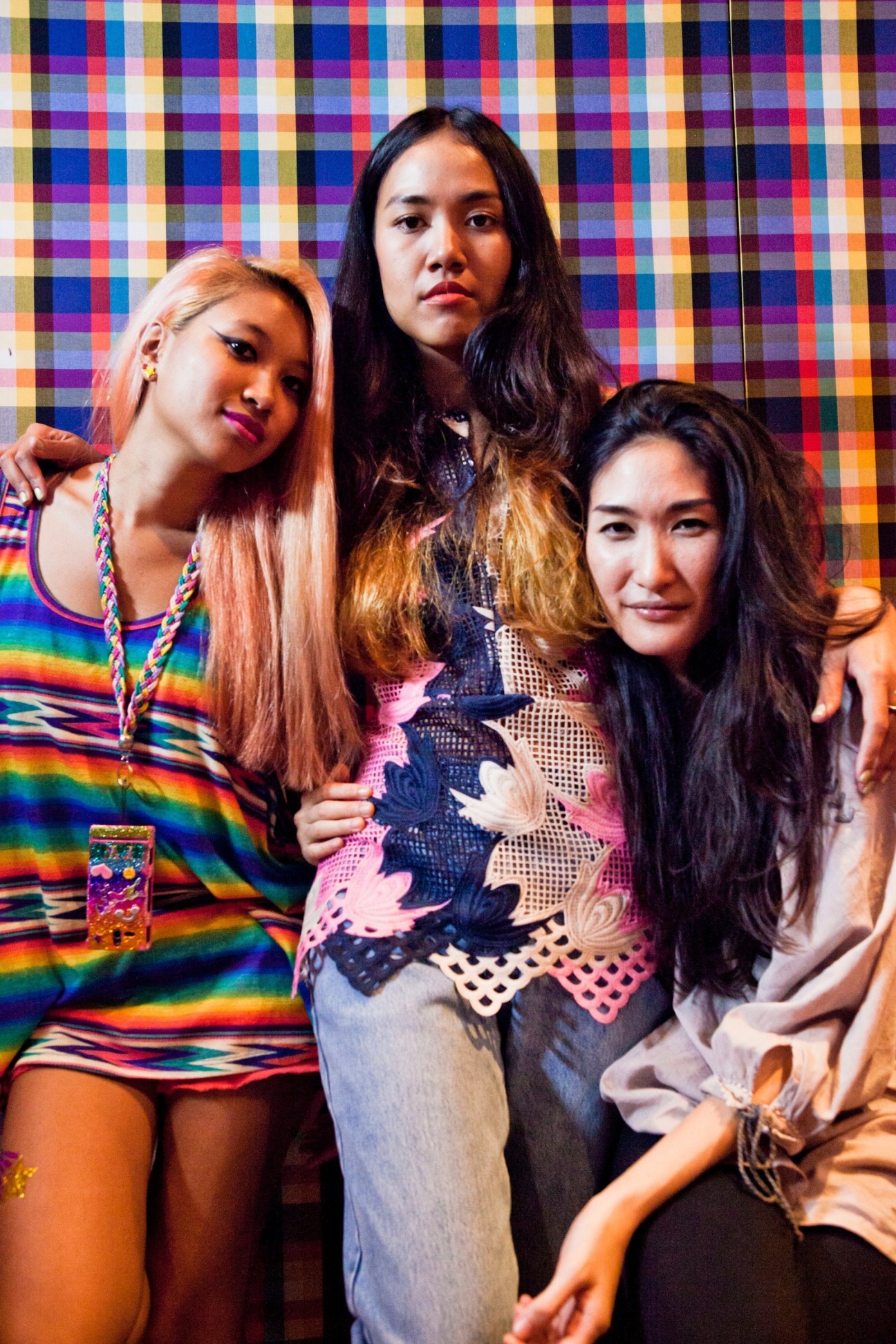 Three young women from Thai indie band Yellow Fang pose against a colorful pixelated backdrop.