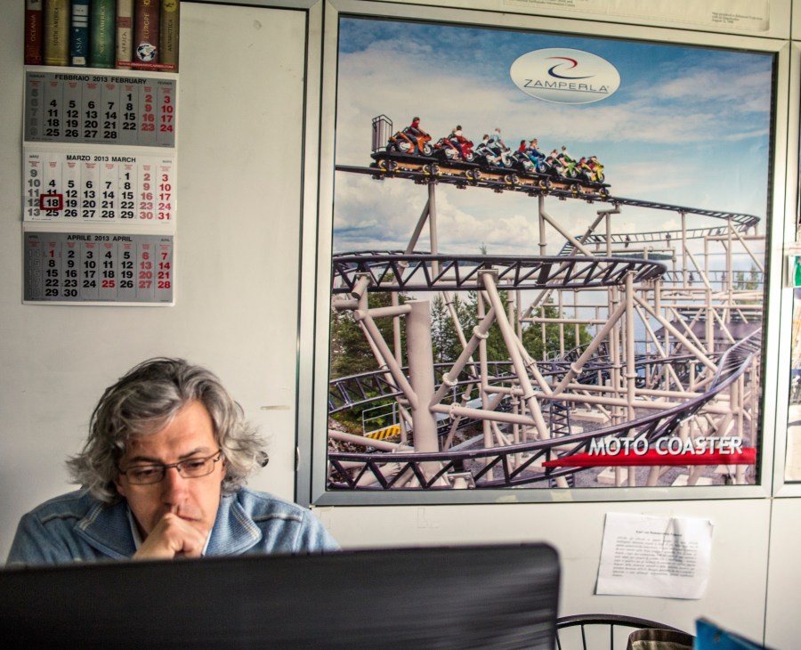 Engineer working at desk with MotoCoaster ride poster on wall behind him.