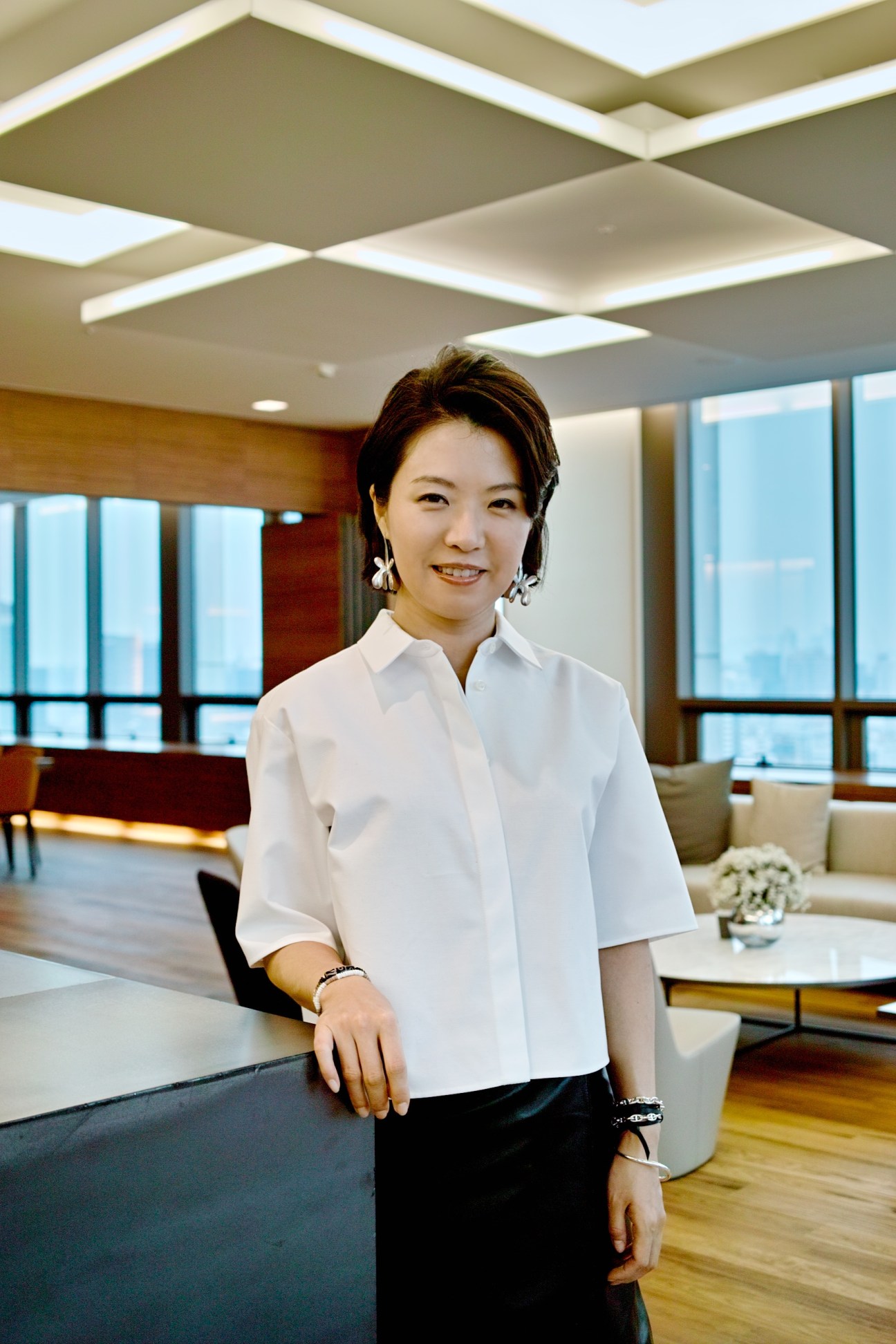 Seung Eun Lee, CEO of SEL Interior Design, poses in Innocean's modern office with wood flooring and glass partitions.
