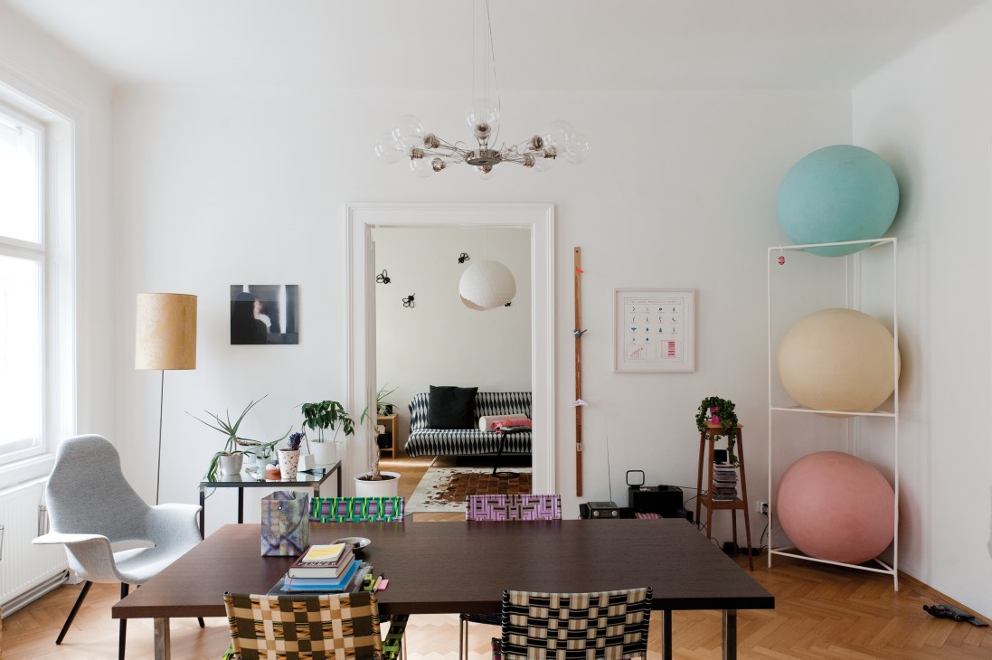 Modern home interior with contemporary furniture, artwork, and colorful sculptural objects displayed on shelving.
