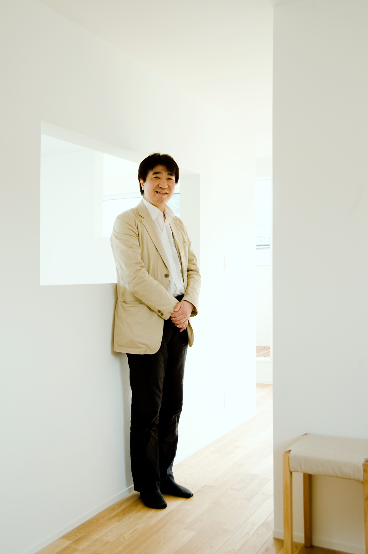 Kazuyoshi Takano, director of Muji's housing division, stands in a minimalist white interior space.