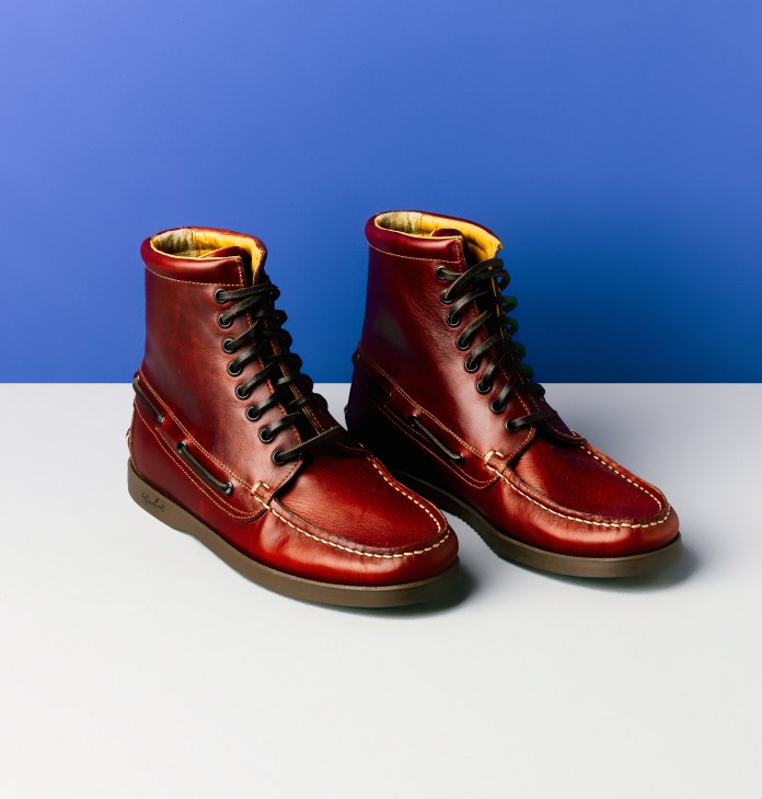 Pair of red leather Paraboot ankle boots with black laces and tan soles against blue and white background.