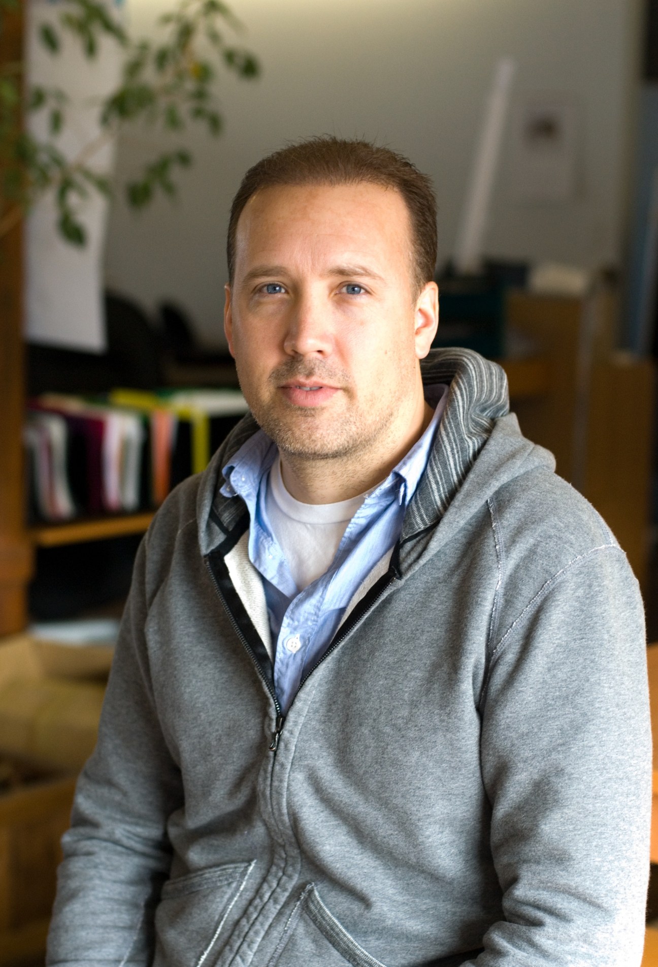 Craig Atkinson, president of CYC Design Corp, wearing a gray zip hoodie and blue shirt in an office setting.