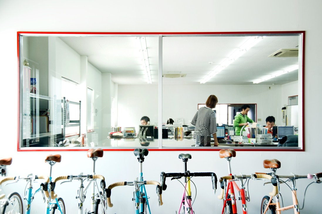 Colorful Funriki bicycles lined up outside the Diatech office in Uji with an interior view visible through windows.