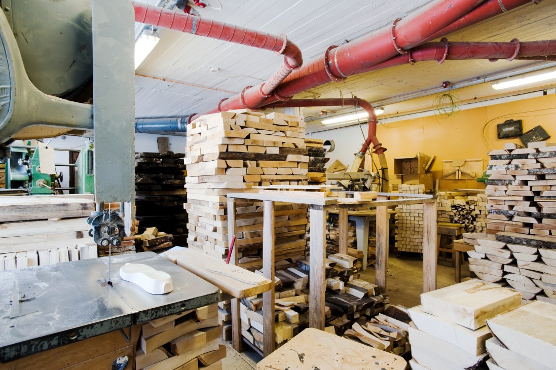 Interior of Talla clog factory workshop with stacks of wood and industrial equipment.