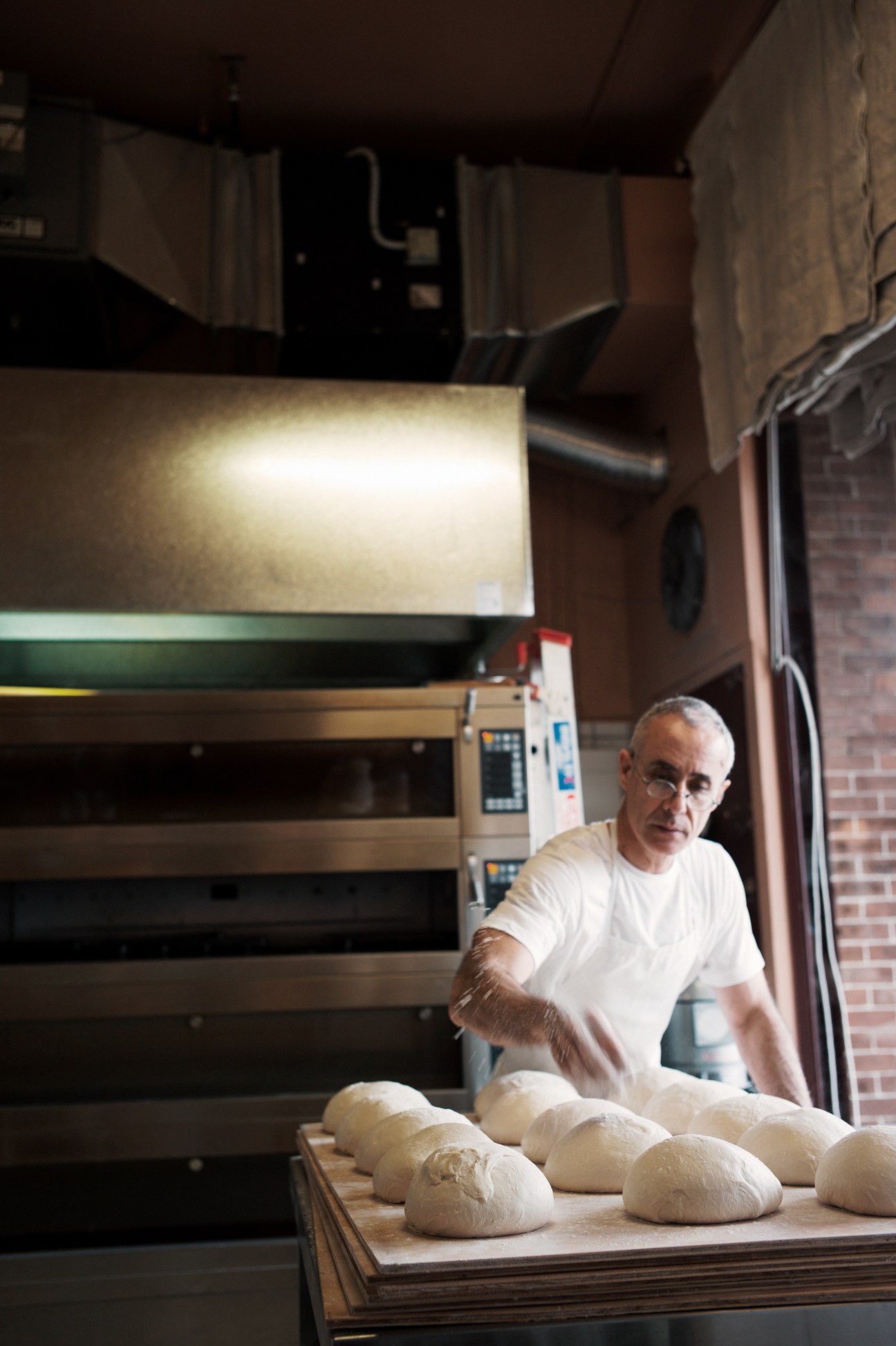 Baker Simon Cancio at Brickfields bakery with fresh loaves and commercial oven.