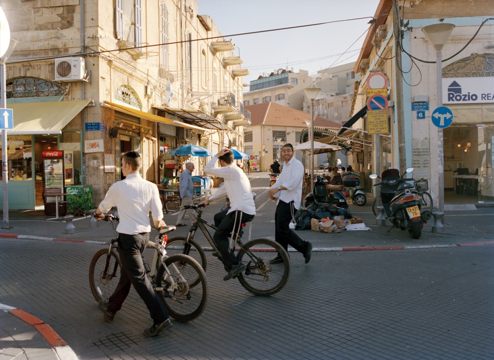 Ultra Orthodox young Israeli Jews ride bicycles through Jaffa's flea market street.