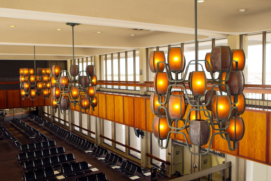 Interior of Honolulu airport with distinctive amber pendant lights, wooden wall paneling, and black seating.