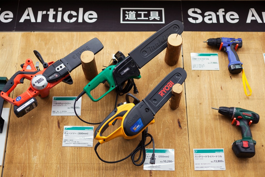 Power saws and drills displayed on wooden table with price tags at Tokyu Hands.