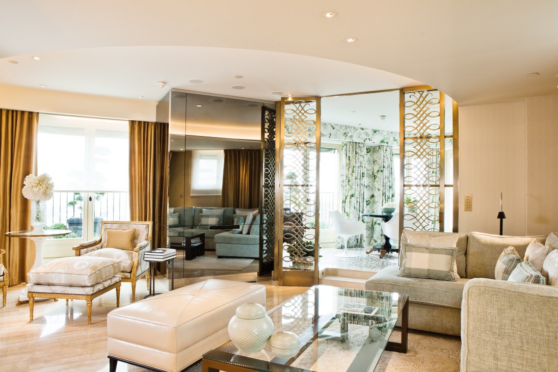 Luxurious penthouse suite interior with gold curtains, cream seating, and modern geometric room dividers.